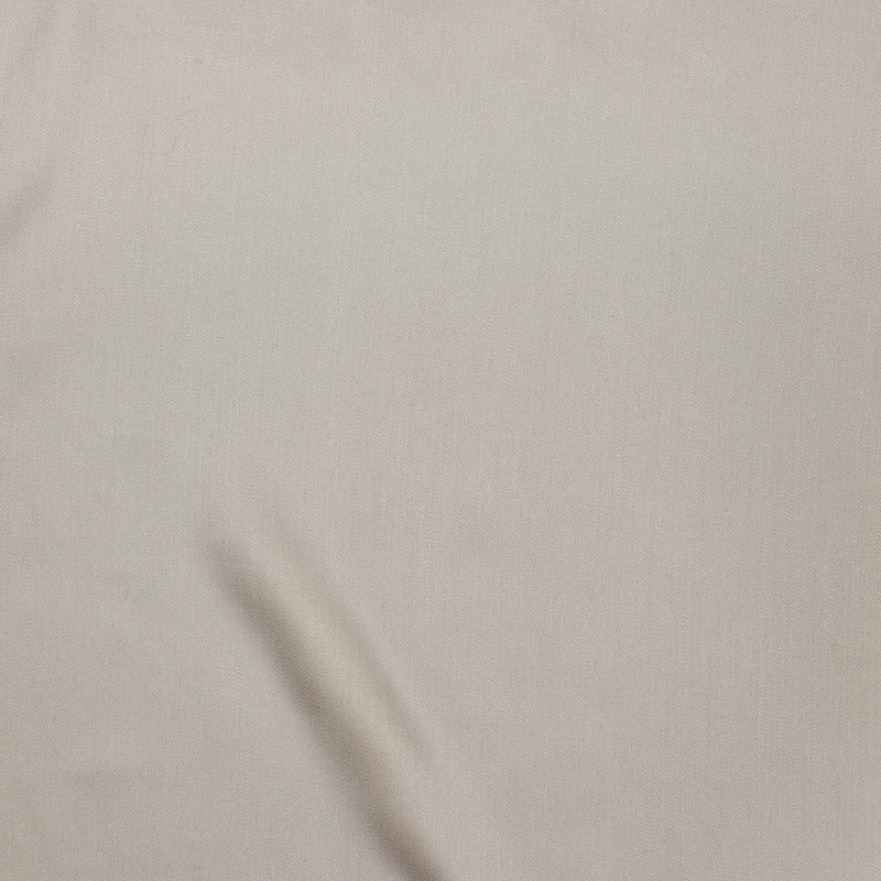 Close-up of ivory fabric with subtle drape and soft woven texture.