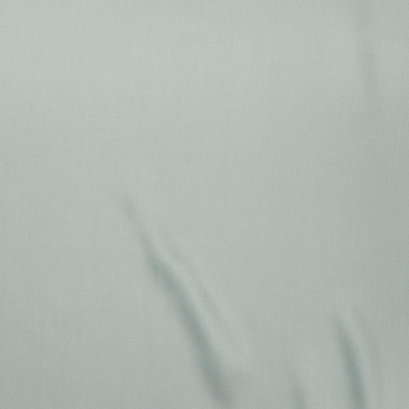 Close-up of pale sage green fabric with soft natural draping and fine linen weave texture.