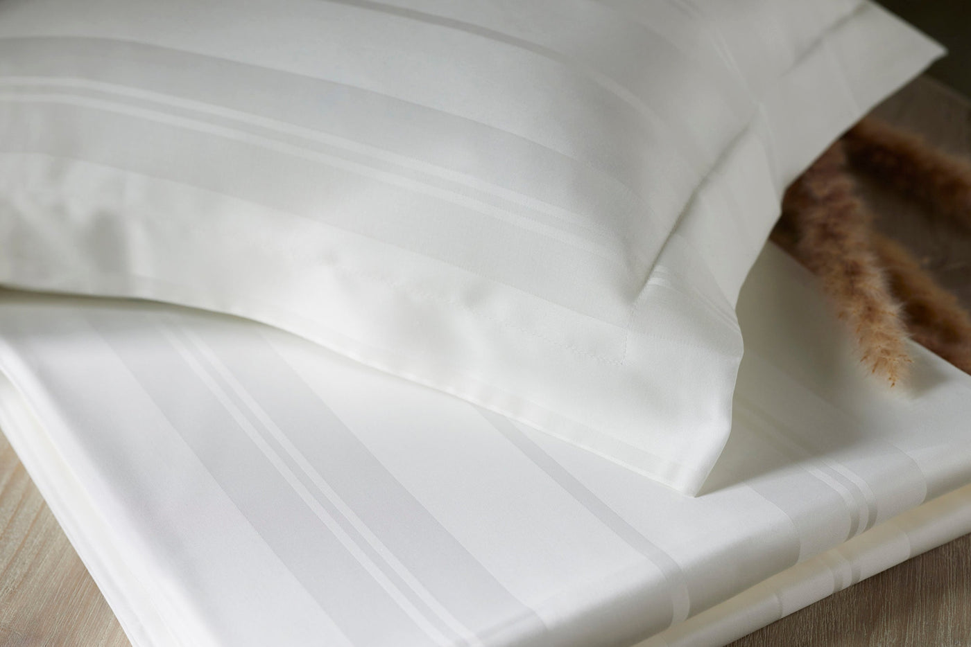 Legna Lucca Stripe bed skirt in ivory, with tone-on-tone satin stripes, styled with matching pillowcase.