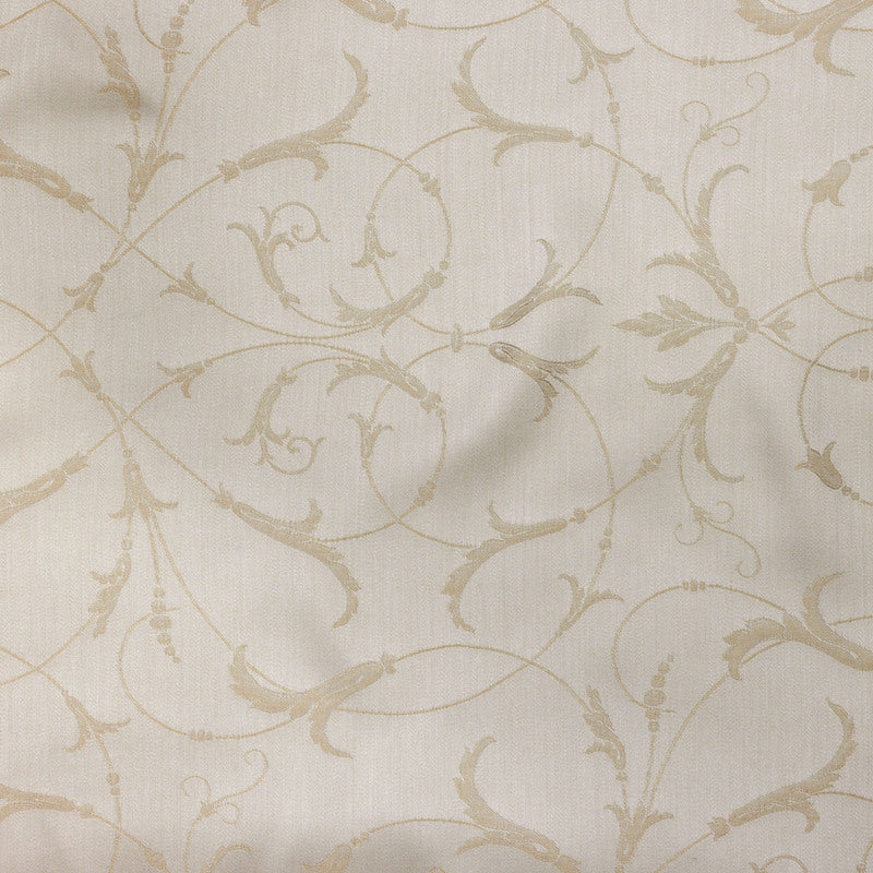 Close-up of Legna Seville pillow fabric, ivory ground with champagne scrolling vine embroidery.