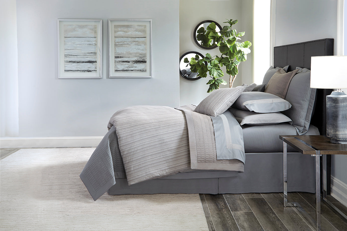 Home Treasures Leonardo bedding styled in silver-grey tones on a made bed with layered pillows.