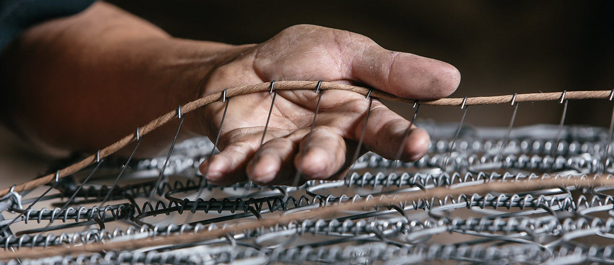 An artisan’s hand on the steel coils of a LETTO mattress during construction