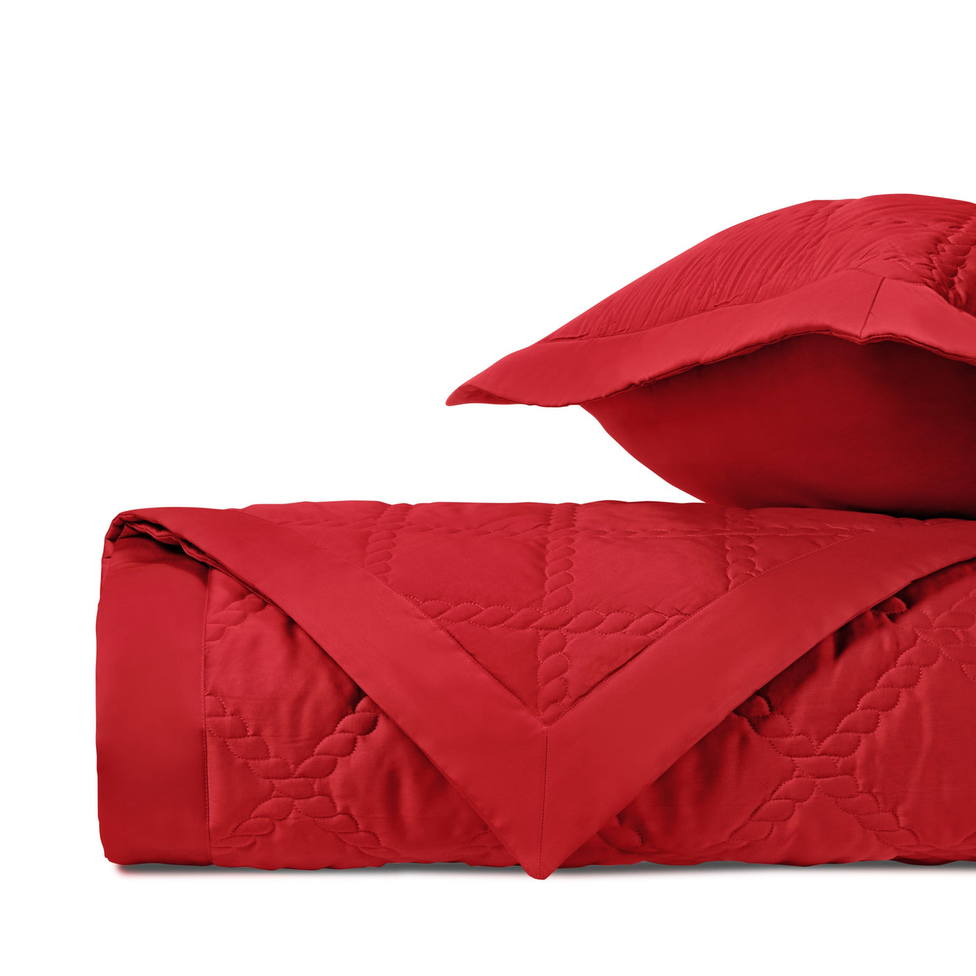 Crimson quilted satin coverlet folded with matching sham, showing geometric stitch pattern.