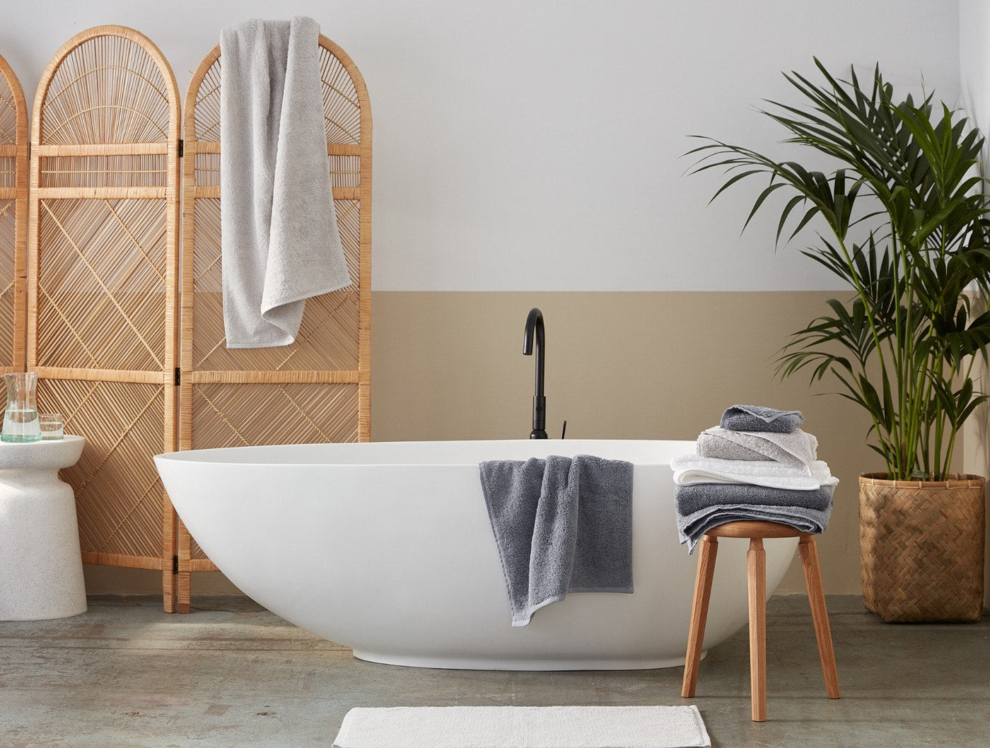 Slate blue Coyuchi Cloud Loom towels styled in a neutral bathroom with freestanding tub.