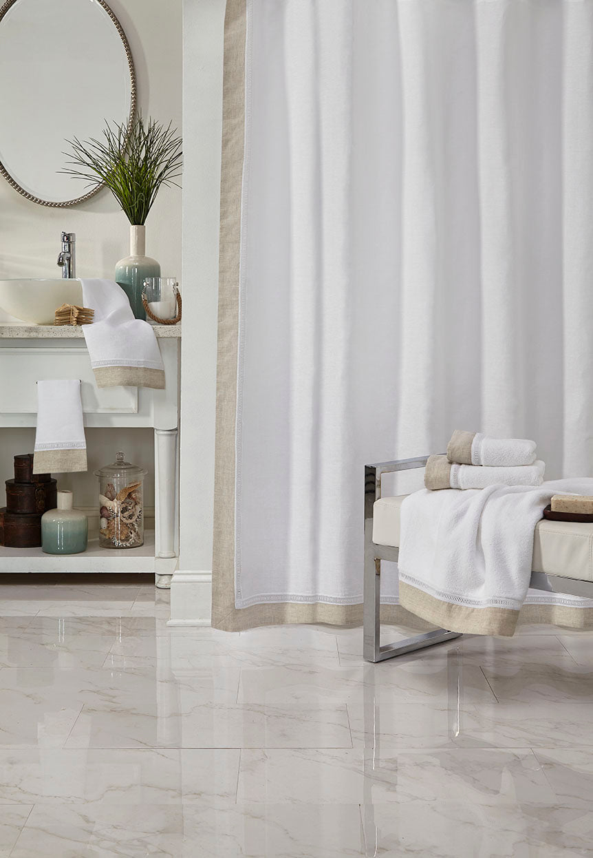 Close-up of Linea towels and shower curtain in white with champagne border trim.