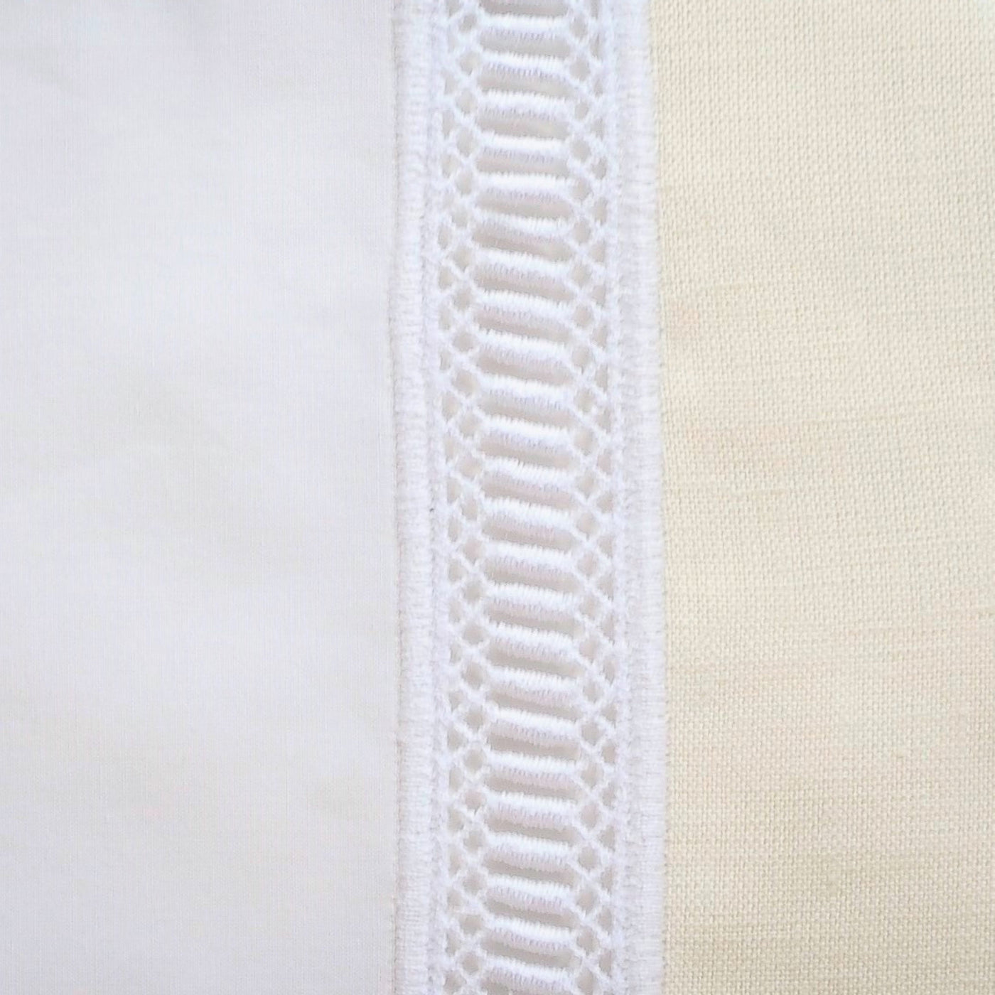 Close-up of white crochet lace trim detail against ivory linen fabric.