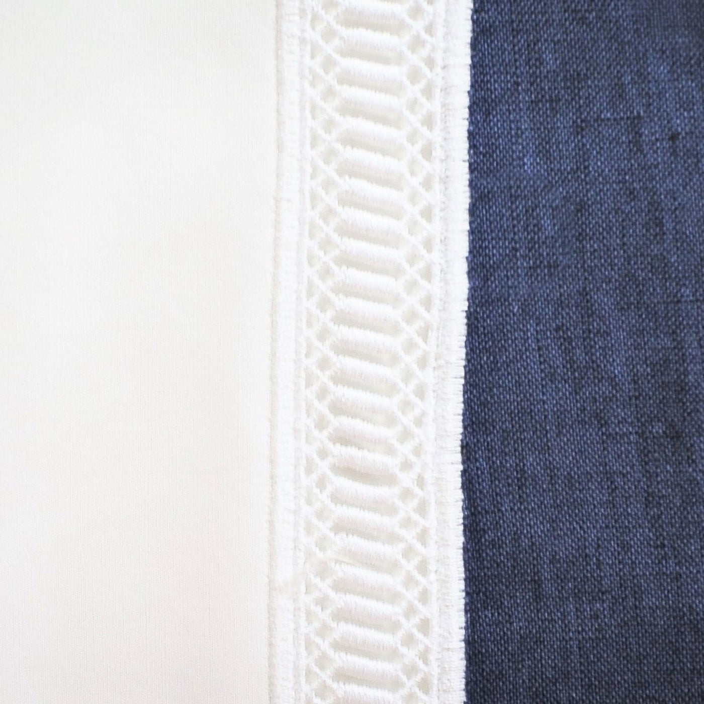 Close-up of ivory crochet lace trim alongside navy linen fabric on Home Treasures Linea placemat.