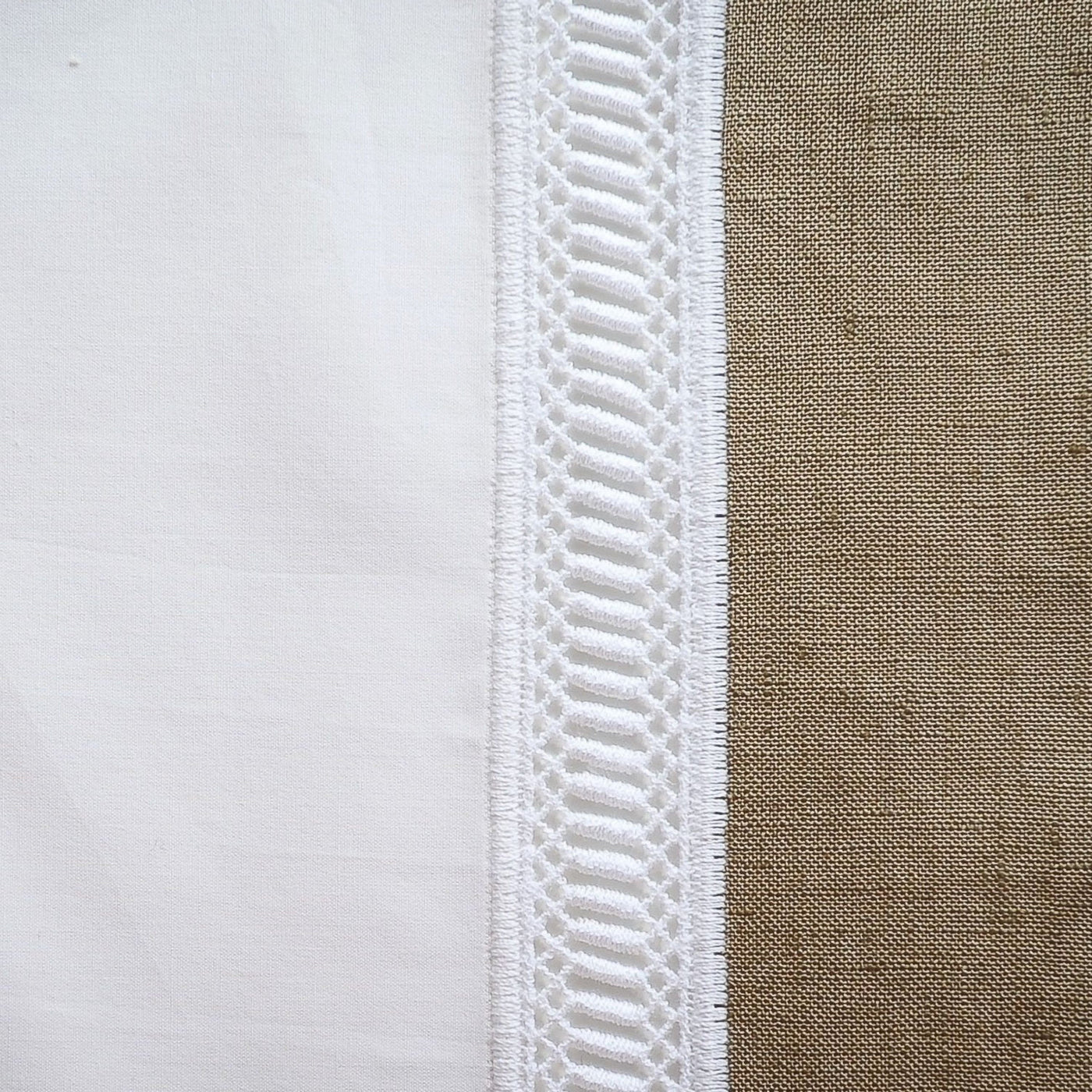 Close-up of white linen tablecloth edge with textured ladder lace trim detail.