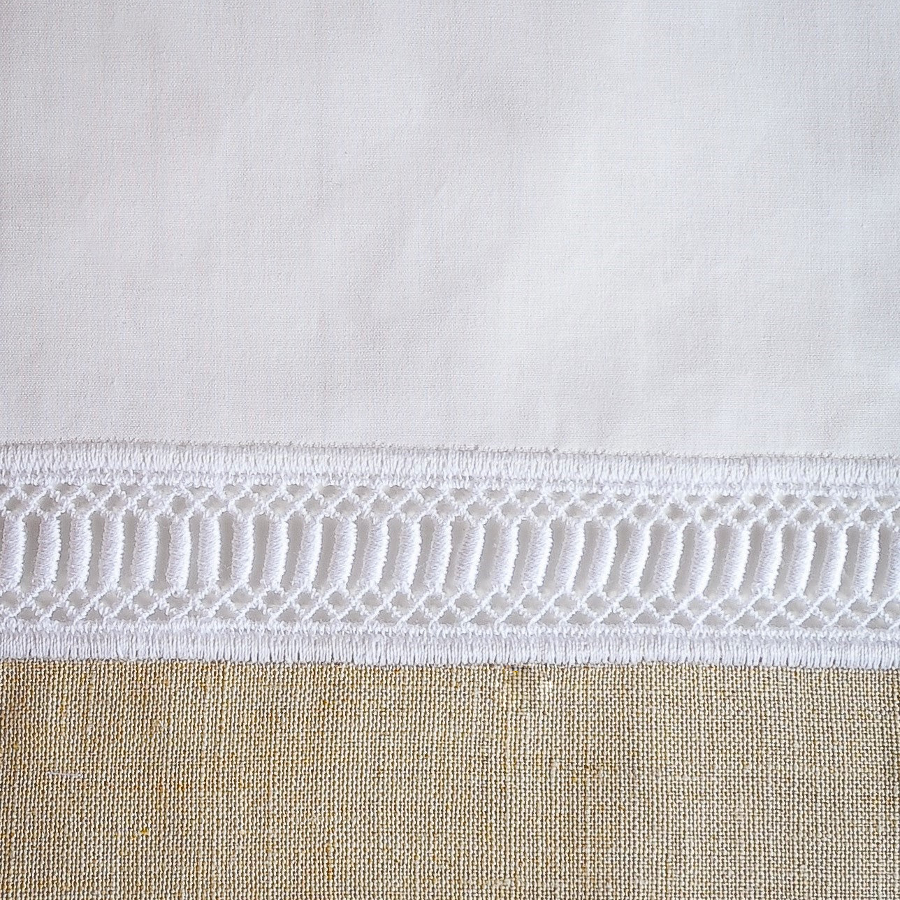 Close-up of white geometric lace trim border on Home Treasures Linea pillow sham.