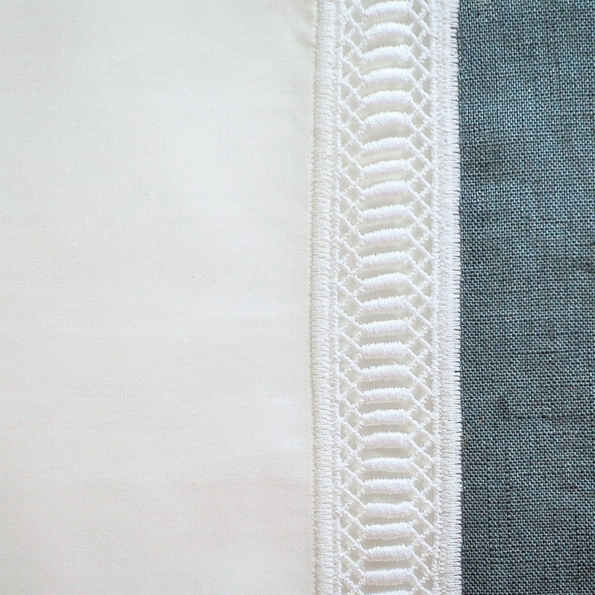 Close-up of ivory linen hem with textured ladder embroidery trim detail.