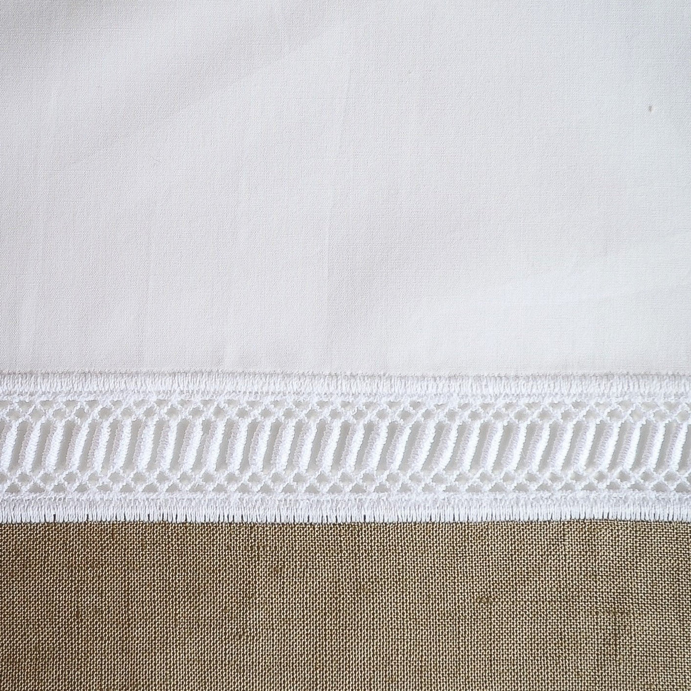 Close-up of white cotton hem with intricate lattice lace trim detail.