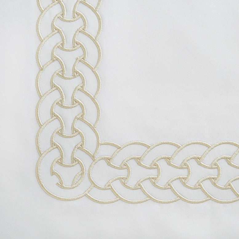 Corner detail of ivory duvet cover with champagne chain-link embroidered border.