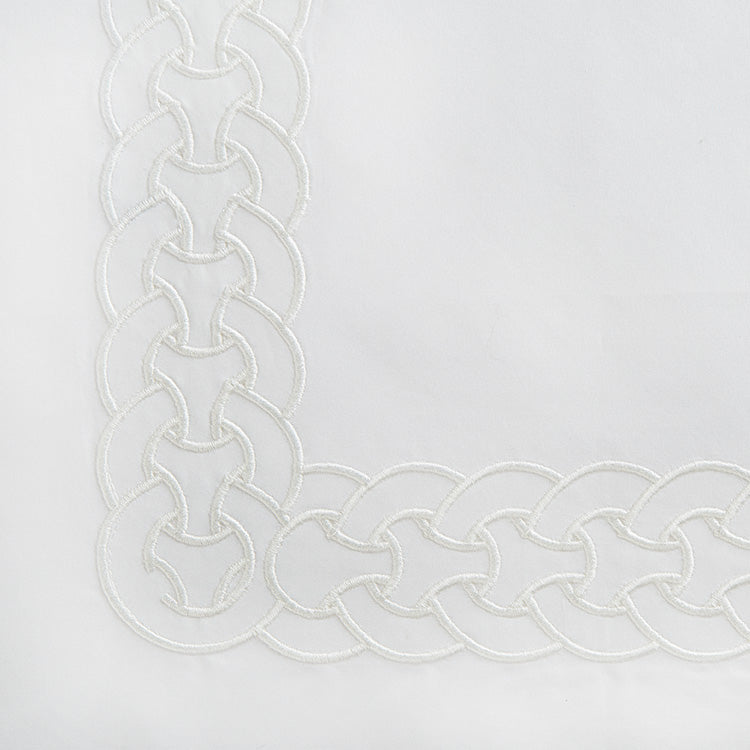 Corner detail of Home Treasures Links flat sheet showing ivory chain-link embroidery border.