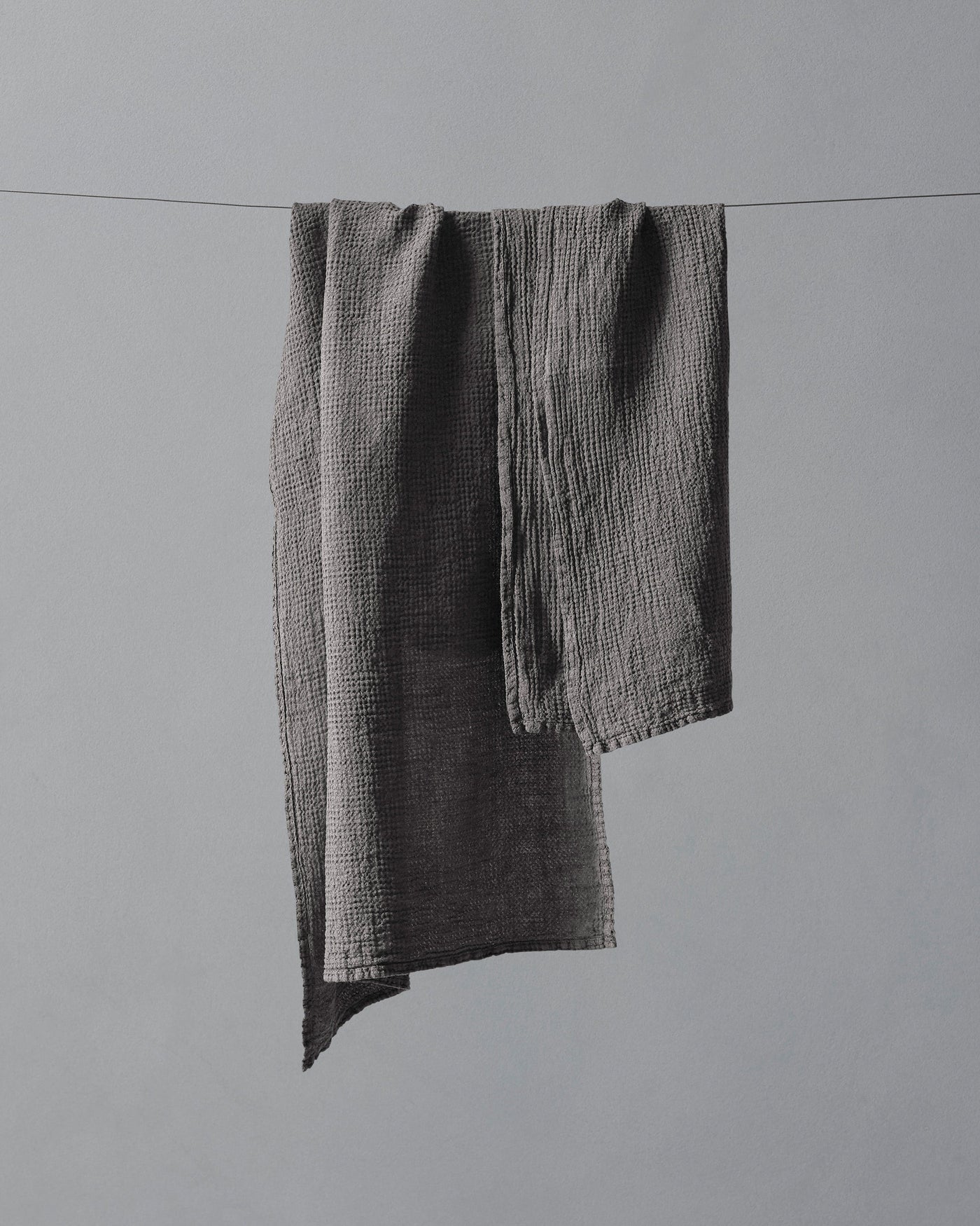 Charcoal crinkle-textured cotton hand towels draped over a clothesline.