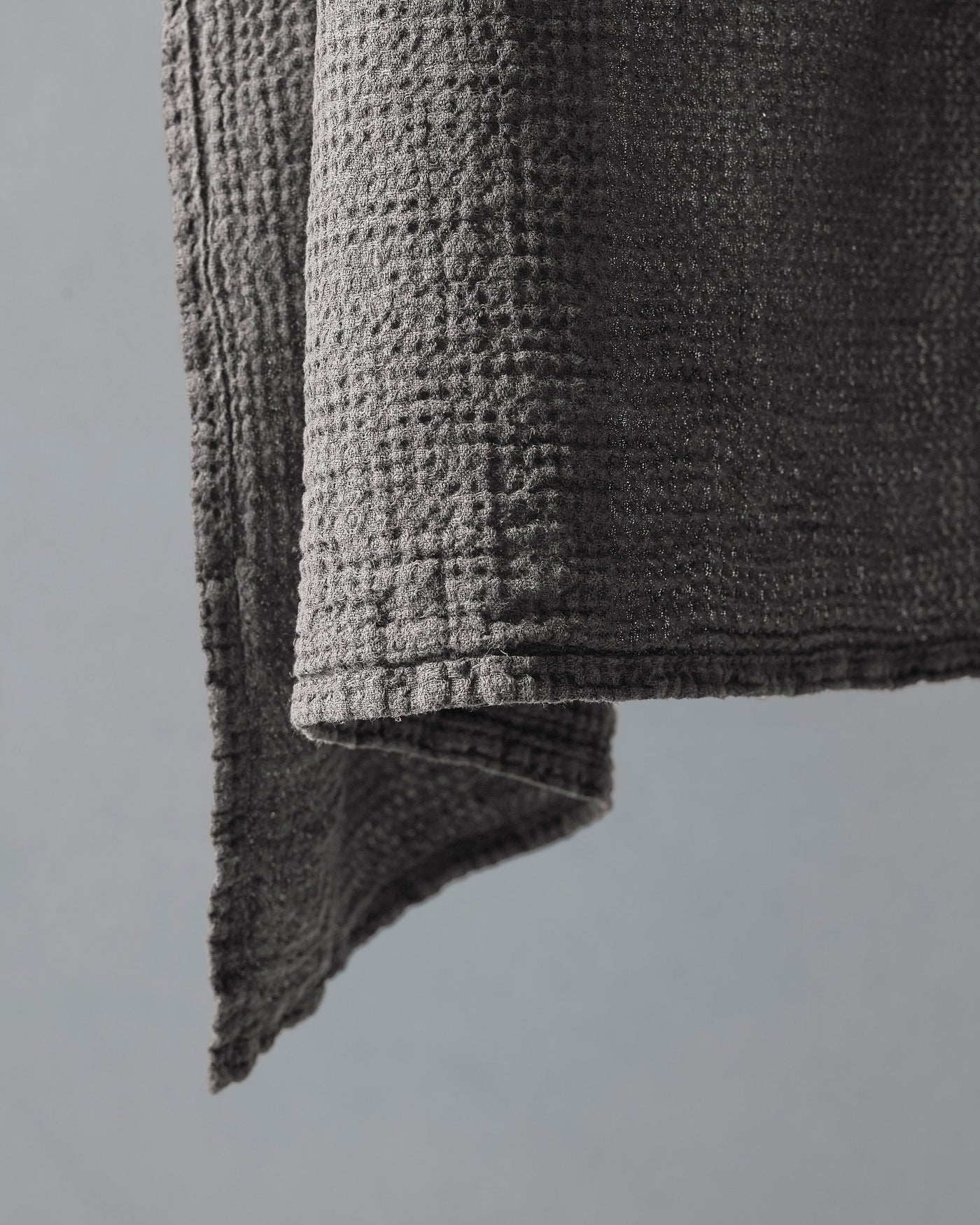 Close-up of charcoal waffle-weave texture and folded hem on Society Limonta Lipe New hand towel.