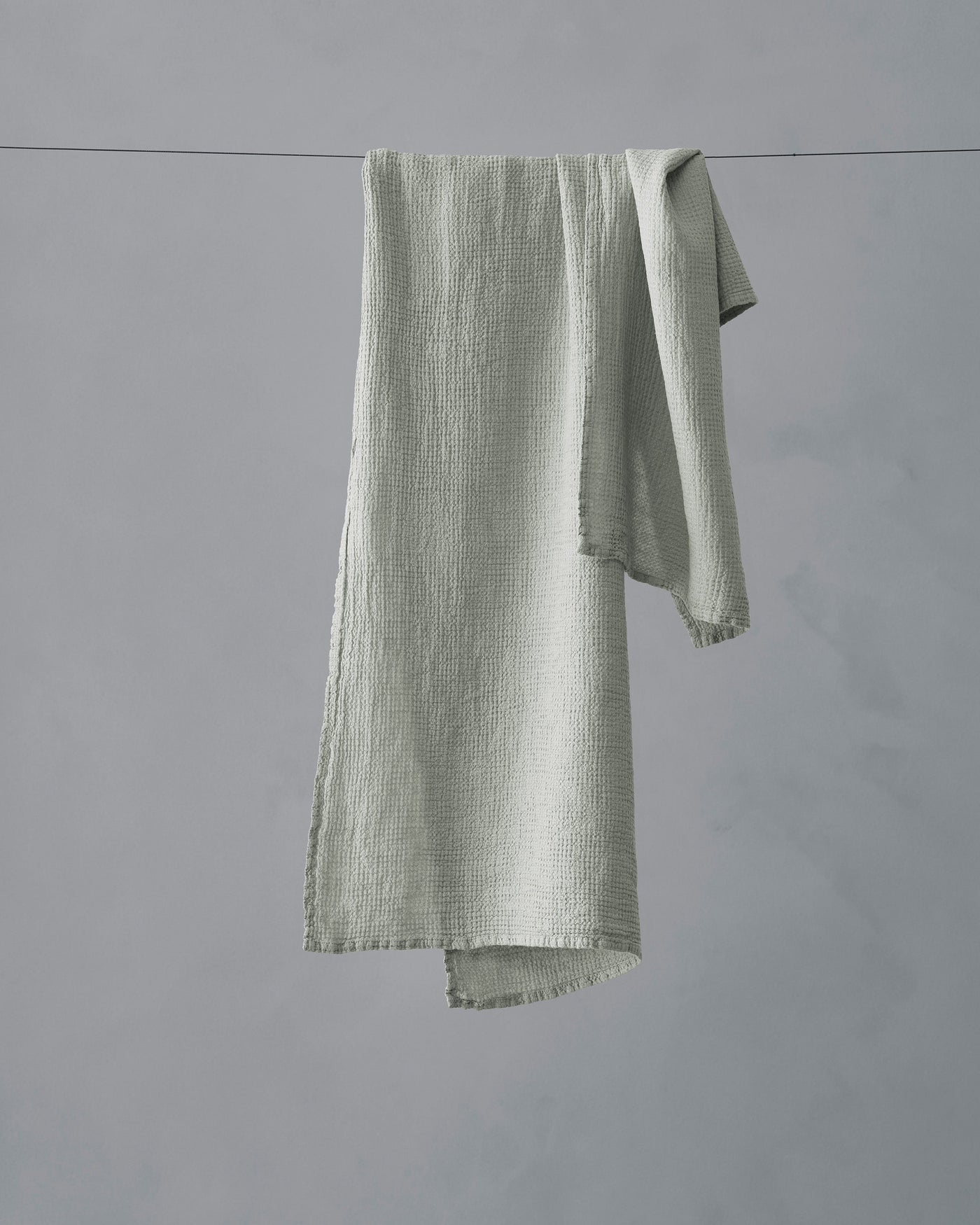 Society Limonta Lipe New hand towel in sage, draped over a clothesline showing textured gauze weave.