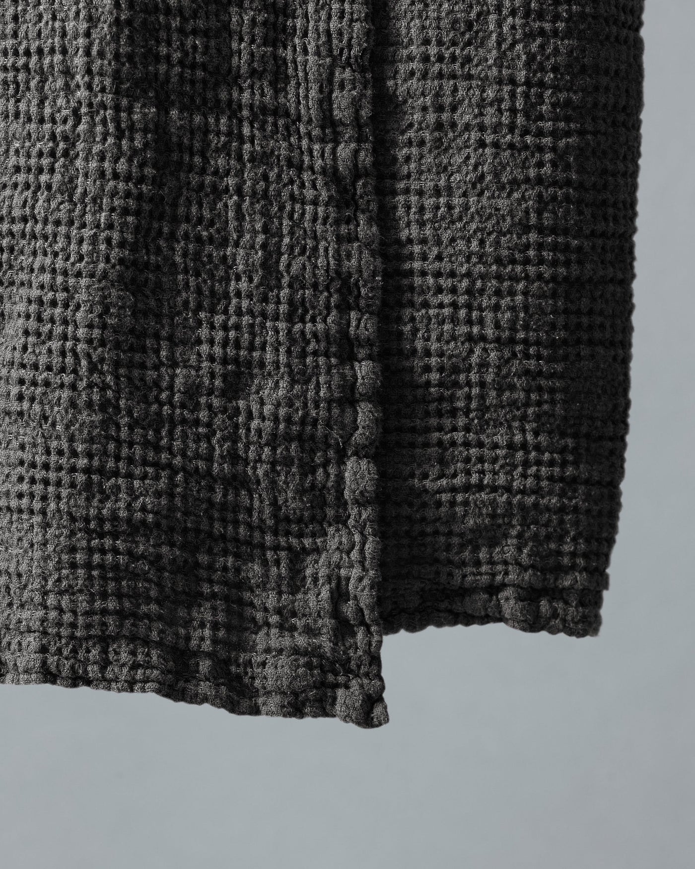 Close-up of charcoal waffle-weave texture and hemmed corner of Society Limonta Lipe New bath towel.