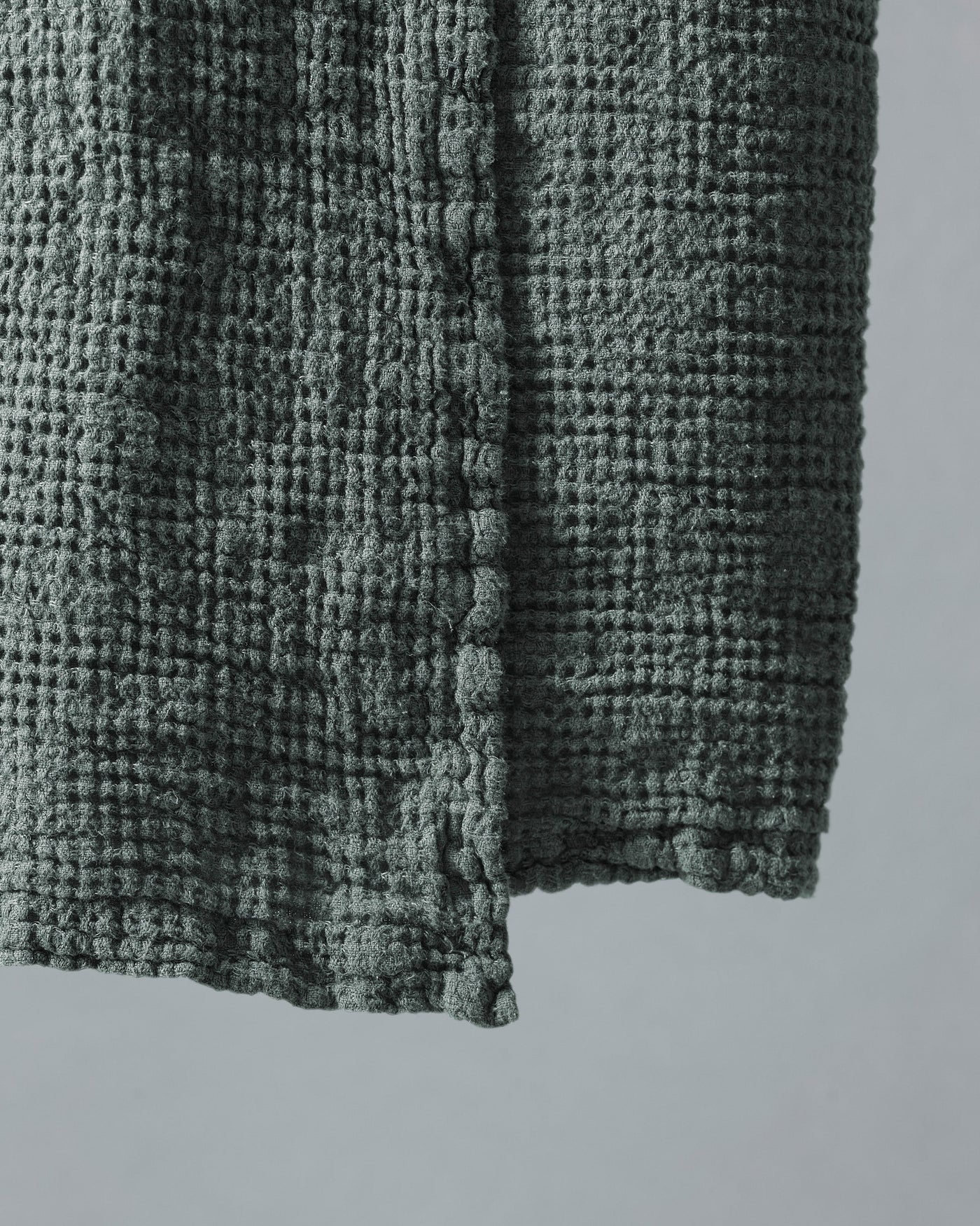 Close-up of sage green waffle-textured cotton corner with raised bobble weave detail.