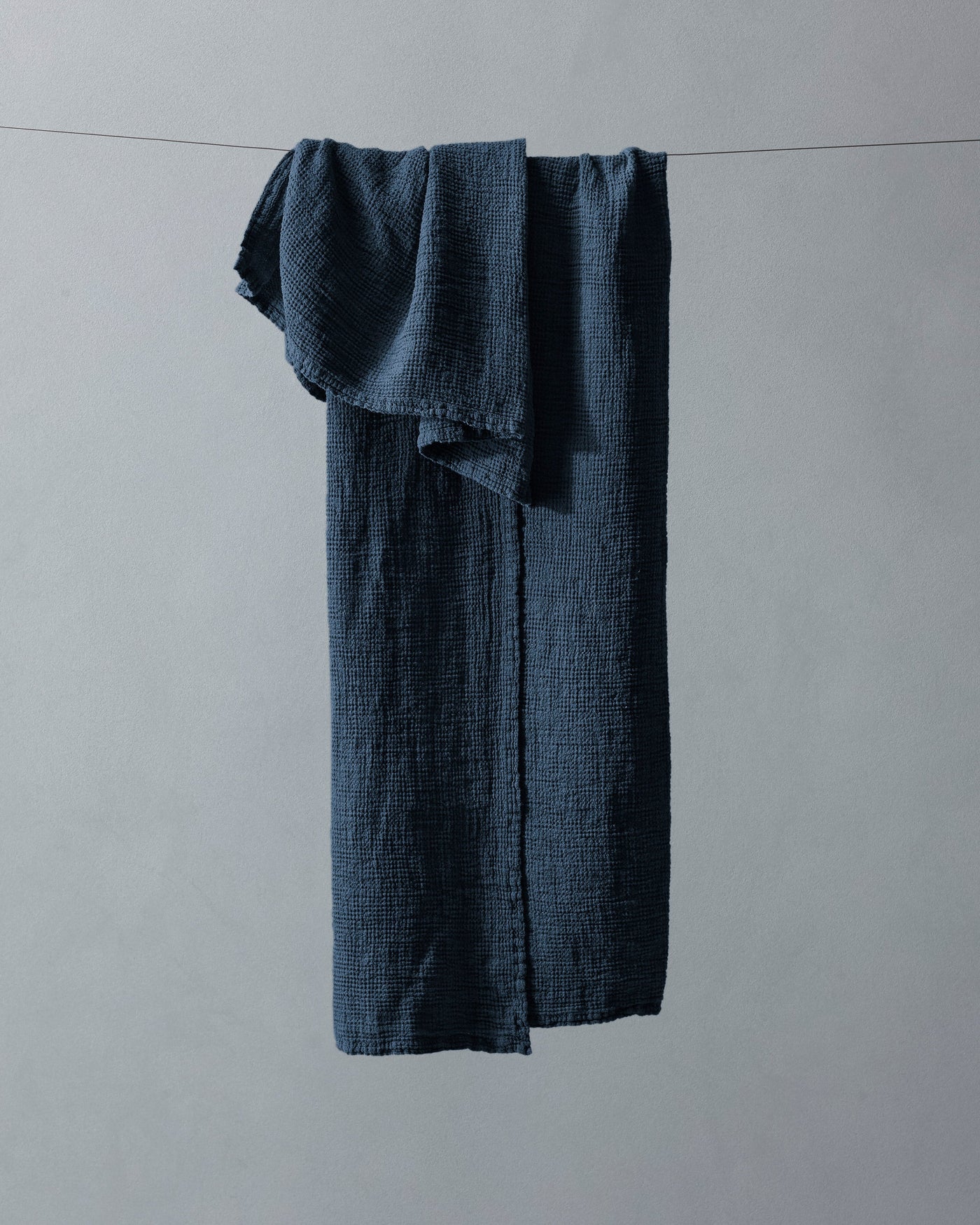 Society Limonta Lipe New navy gauze cotton bath towel draped over a line.