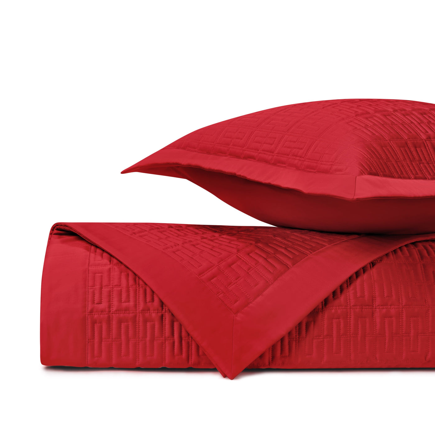 Close-up of crimson quilted coverlet with geometric Greek key stitching, folded with matching sham.