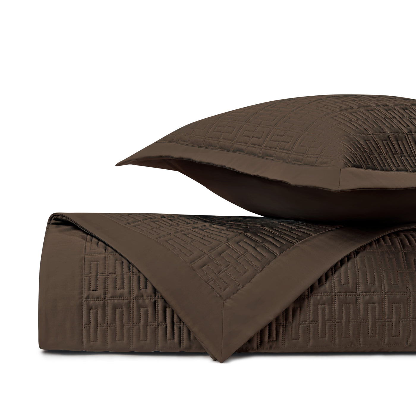 Close-up of chocolate quilted coverlet corner with geometric Greek key stitching pattern.