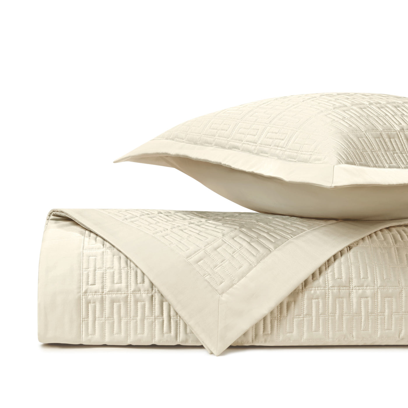 Close-up of ivory quilted satin with geometric Greek key pattern and contrast border.