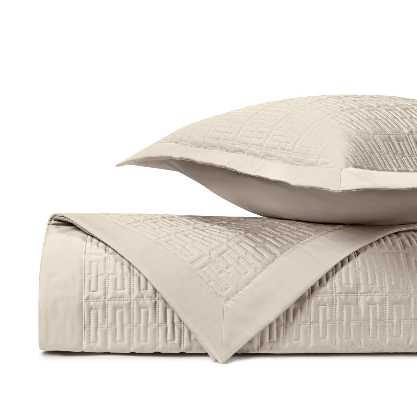 Close-up of ivory quilted coverlet with geometric Greek key pattern and coordinating sham.