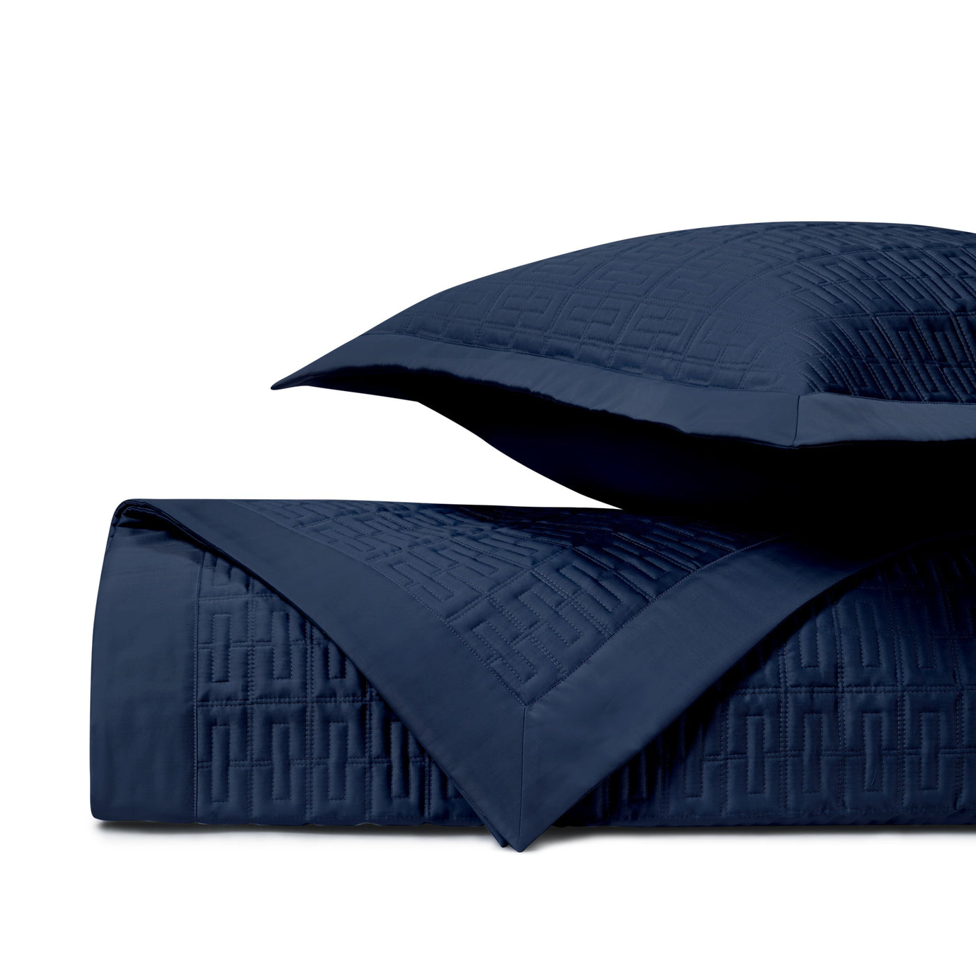 Close-up of navy quilted coverlet with geometric basketweave stitching and matching sham.