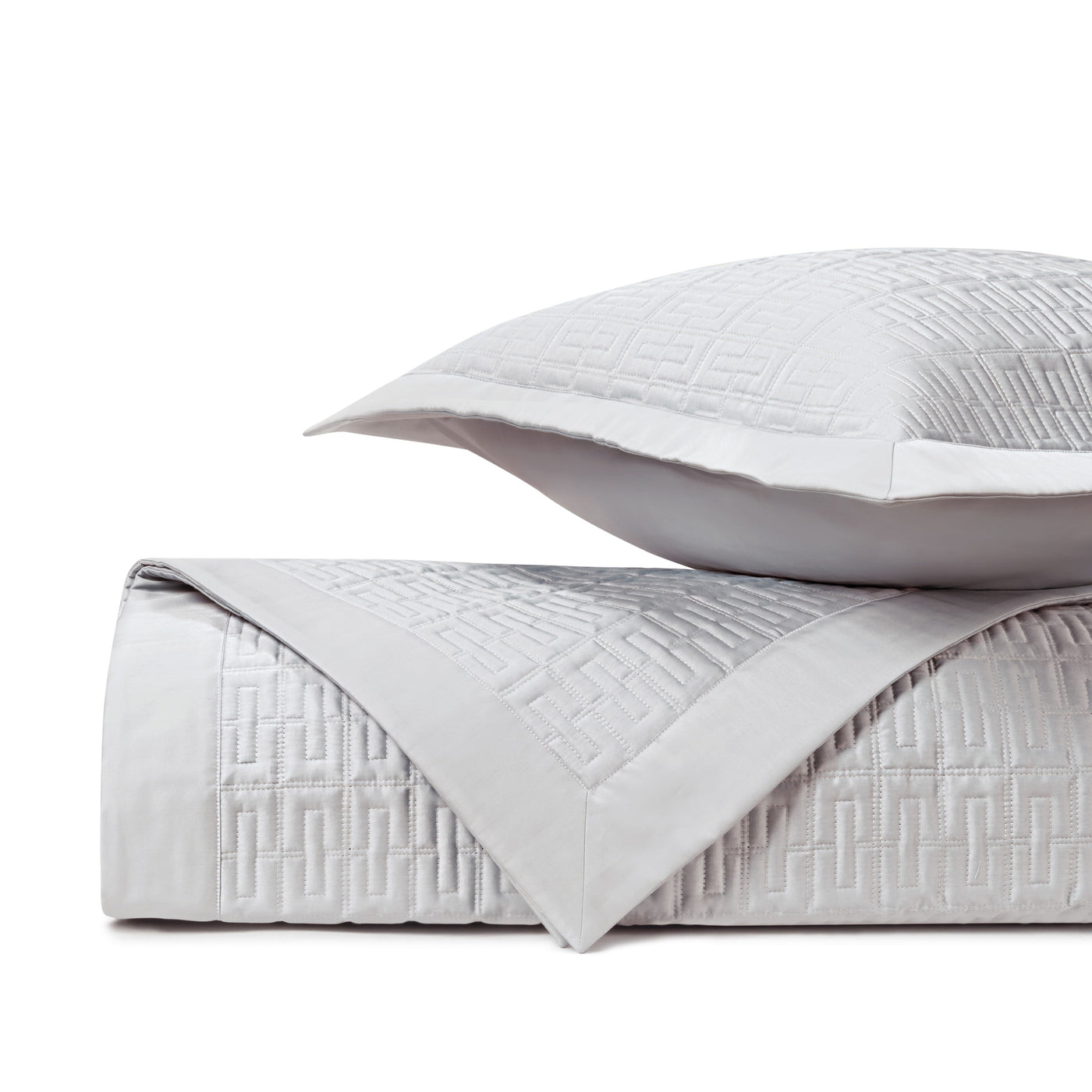 Close-up of quilted geometric Greek key pattern in silver-white cotton.