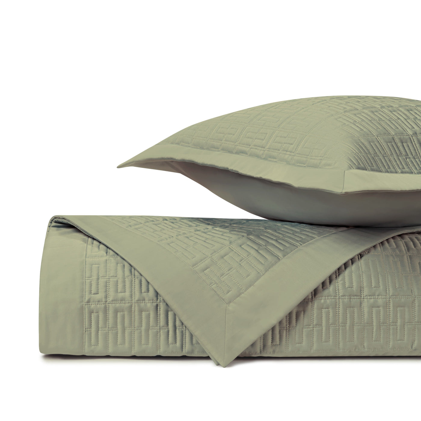 Close-up of sage green quilted coverlet and sham with geometric Greek key stitching pattern.