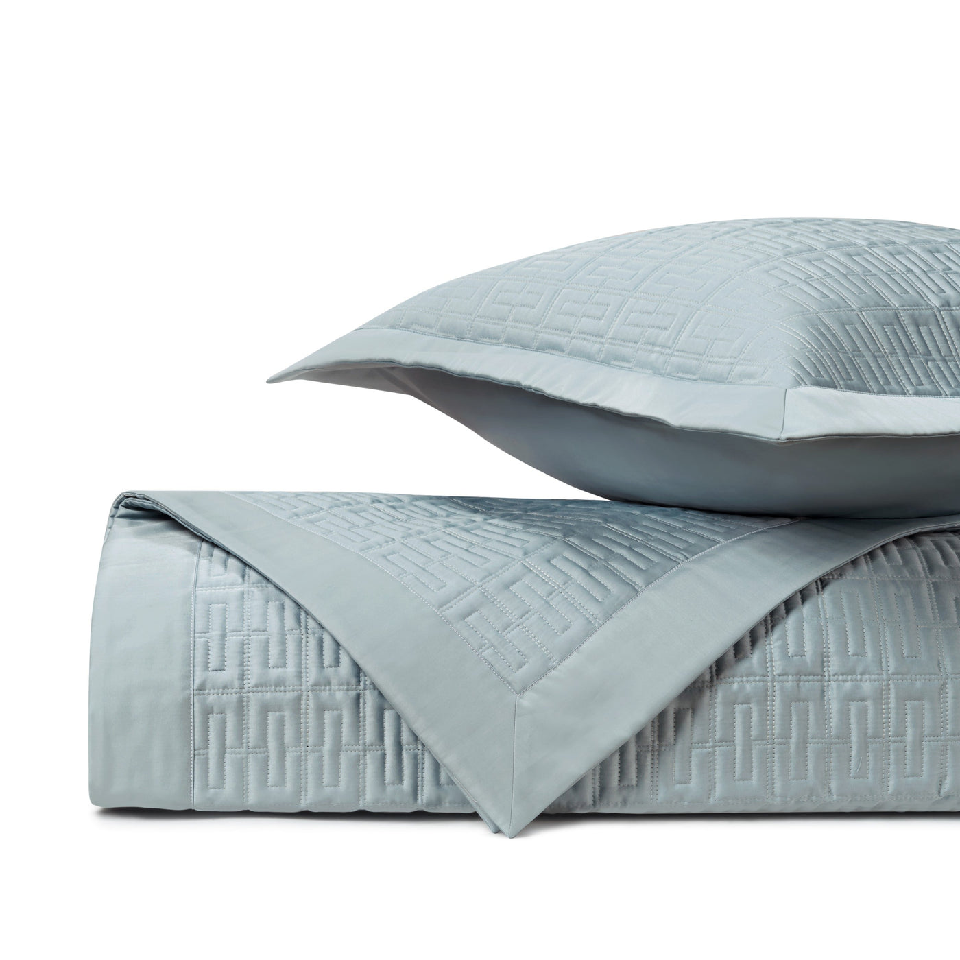 Close-up of mist blue quilted coverlet with geometric Greek key pattern and matching sham.