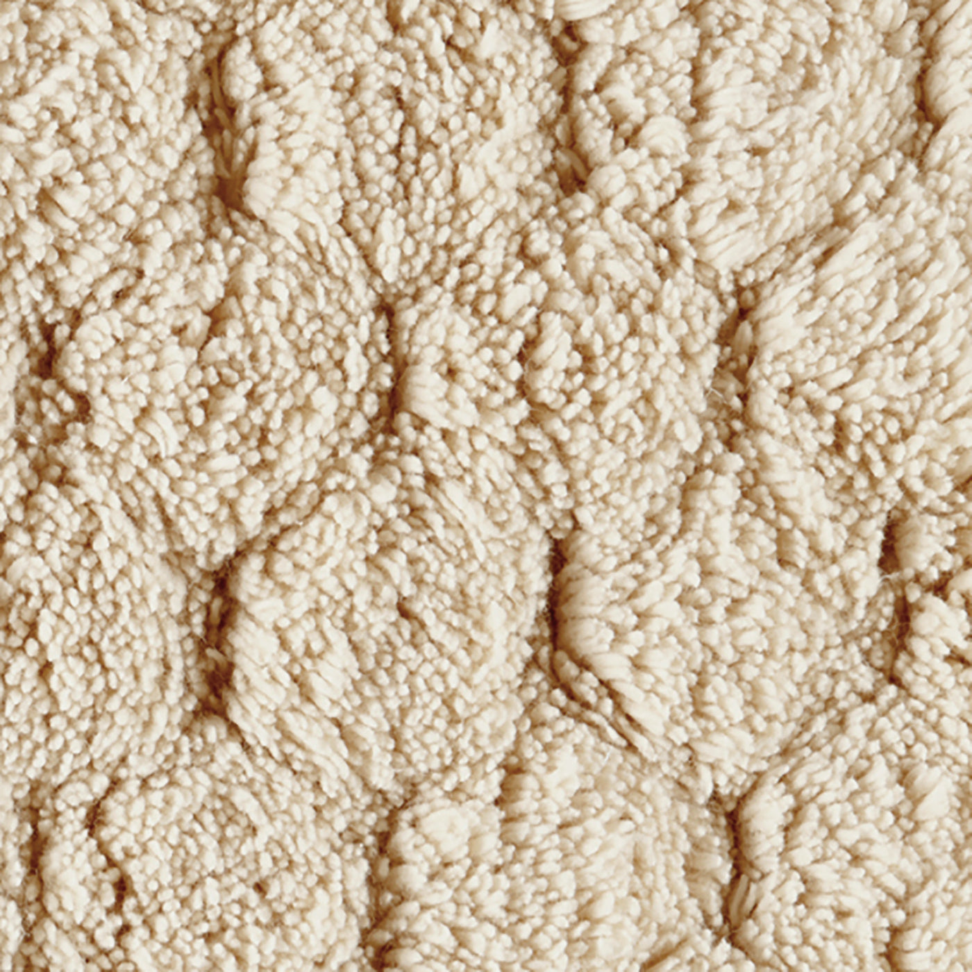 Close-up of ivory Matouk Lotus bath rug showing tufted cable-knit texture.