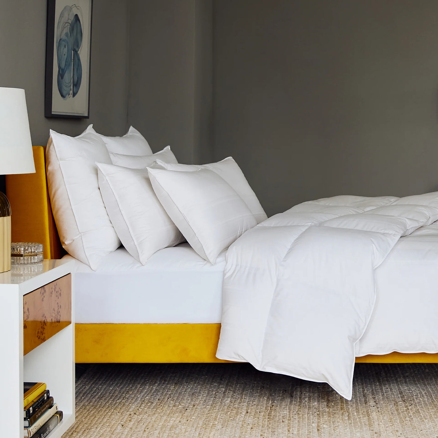 White Scandia Home Lucerne pillow styled on a gold-framed bed with layered white bedding.