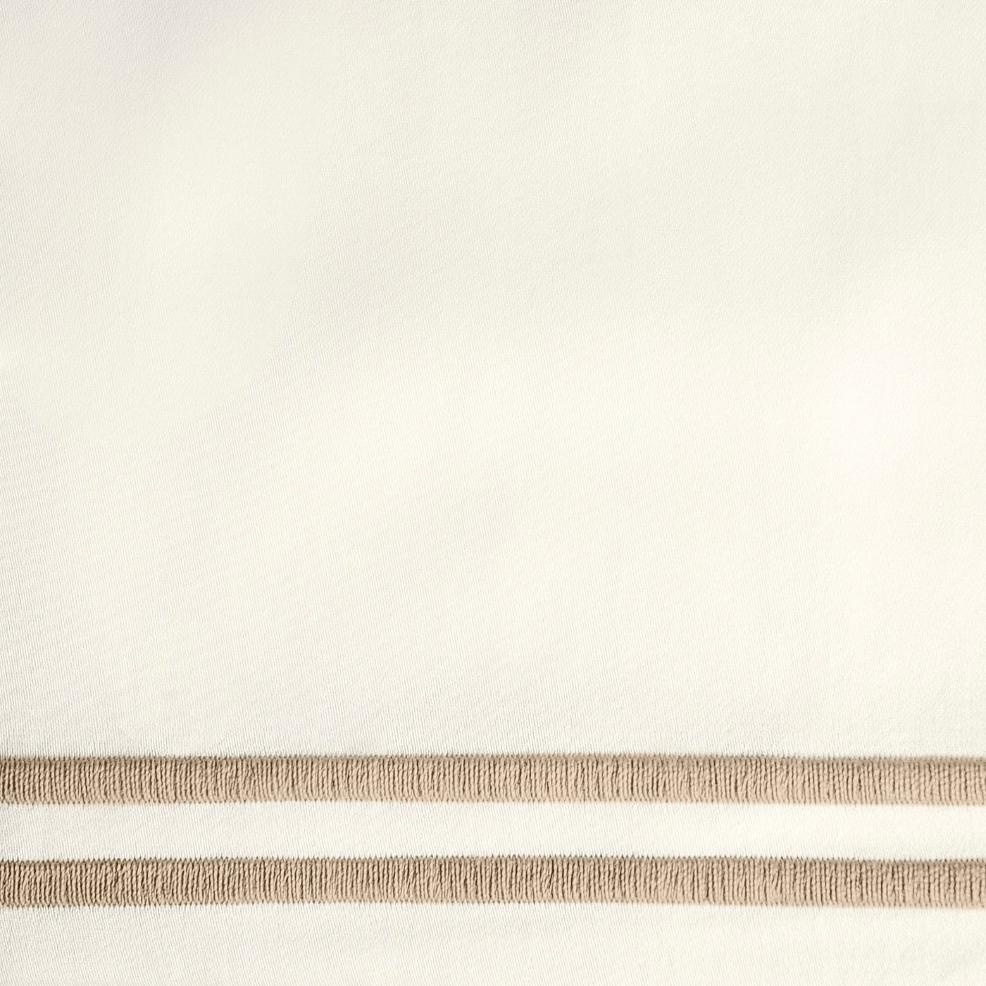 Close-up of ivory fabric with twin champagne embroidered border stripes.