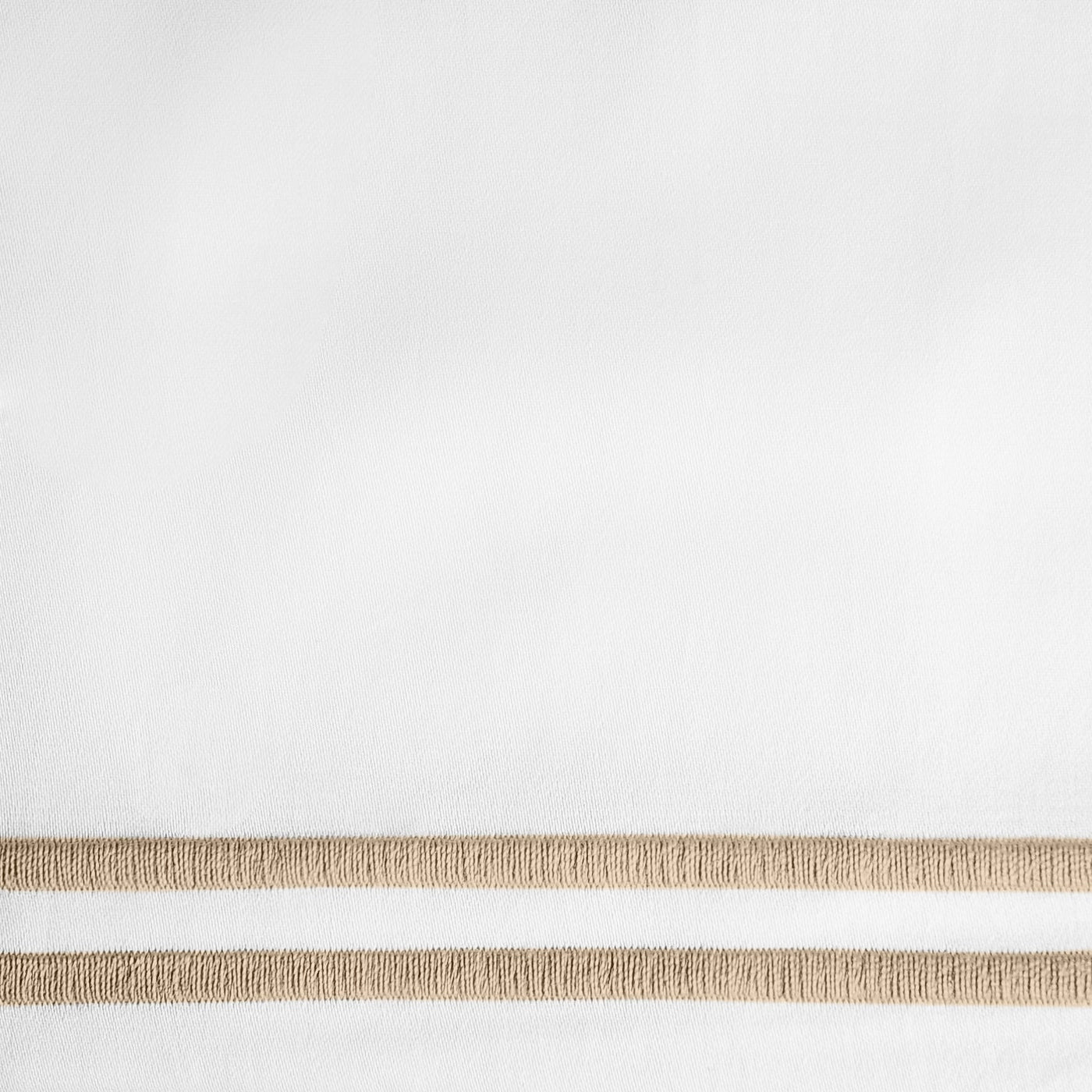 Close-up of white fabric with dual champagne embroidered border stripes.