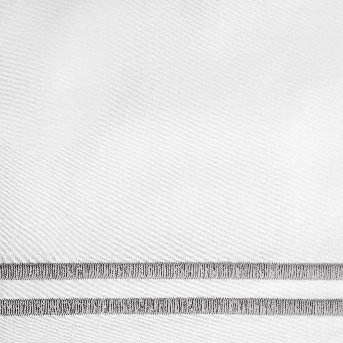 Close-up of white fabric with dual silver embroidered border stripes.