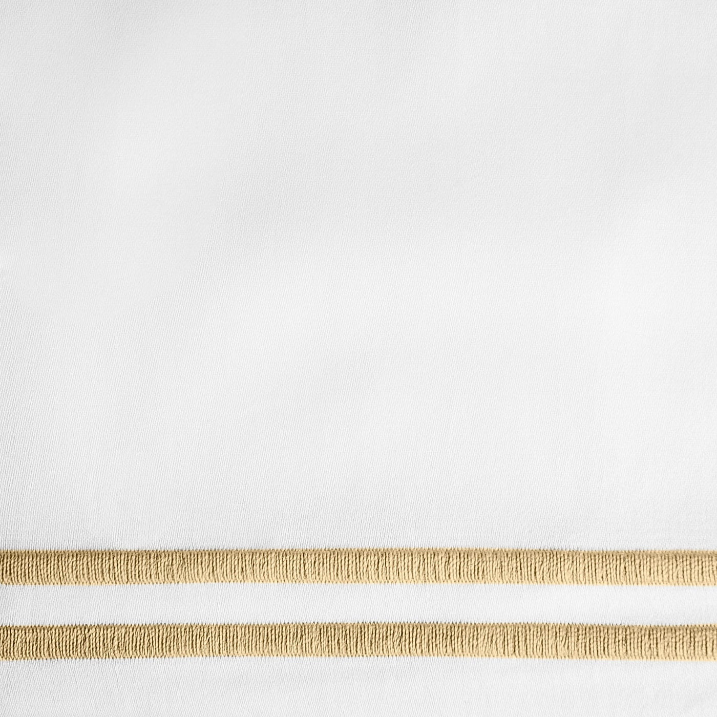 Close-up of white fabric with twin gold embroidered border stripes.