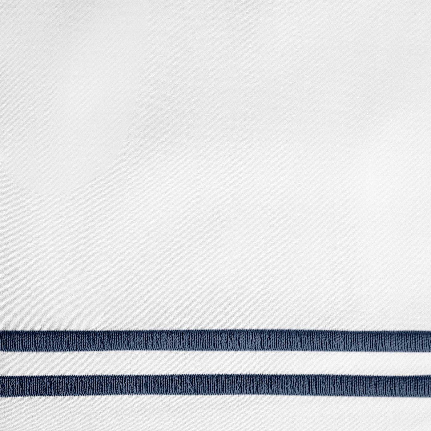 Close-up of white fabric with twin navy embroidered border stripes.