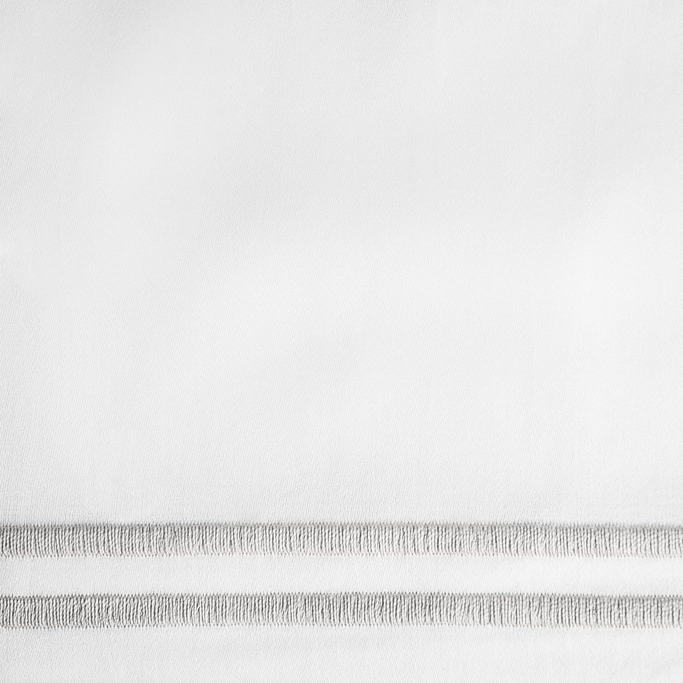 Close-up of white linen with delicate hemstitch ladder detailing along the border.