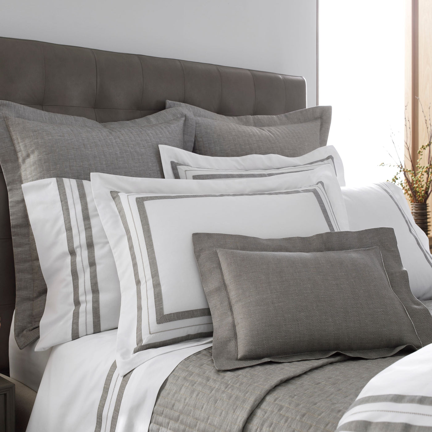 Close-up of Home Treasures Malibu linen bedding in grey and white layered bed styling.