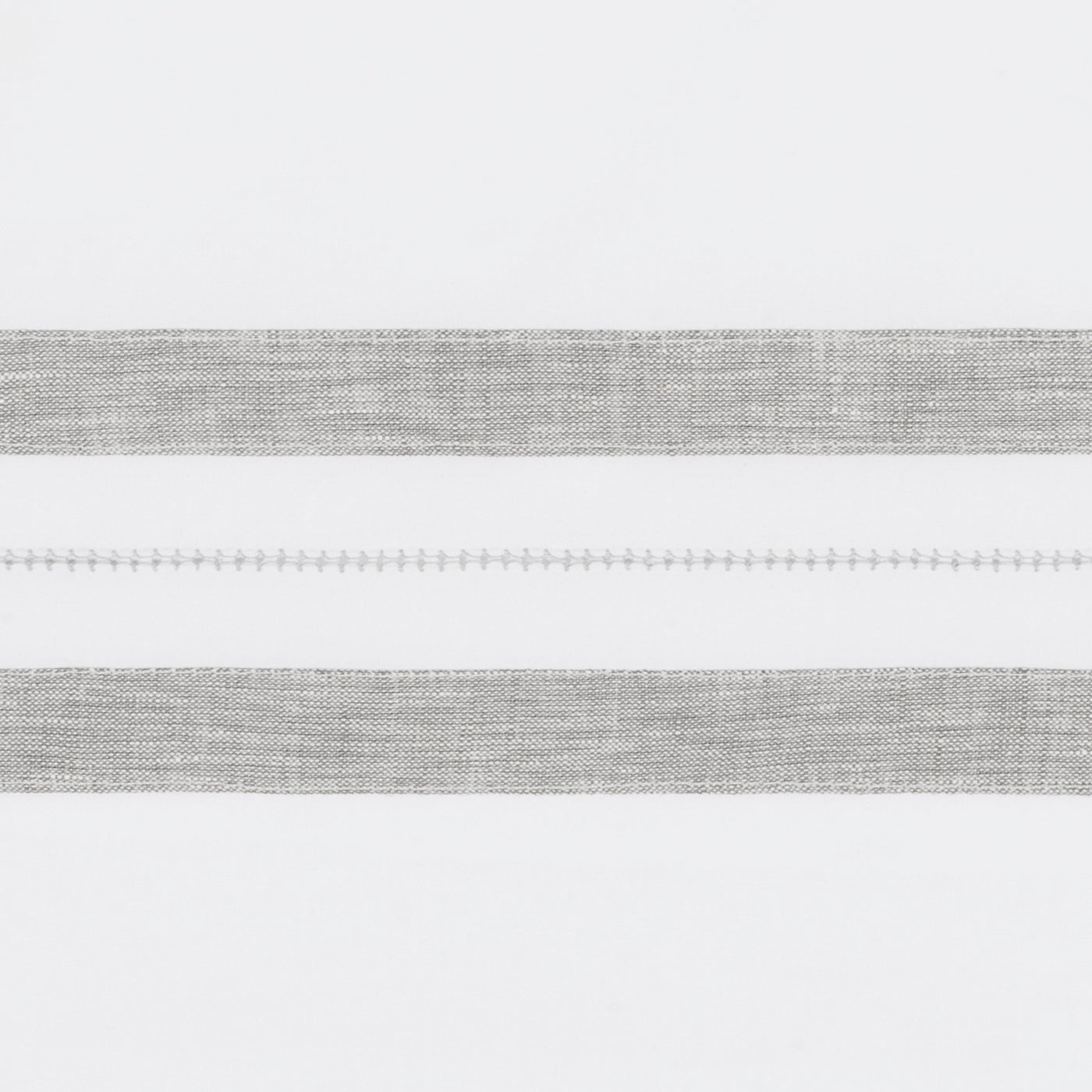 Close-up of silver woven stripe detail with delicate hemstitch accent on white linen.