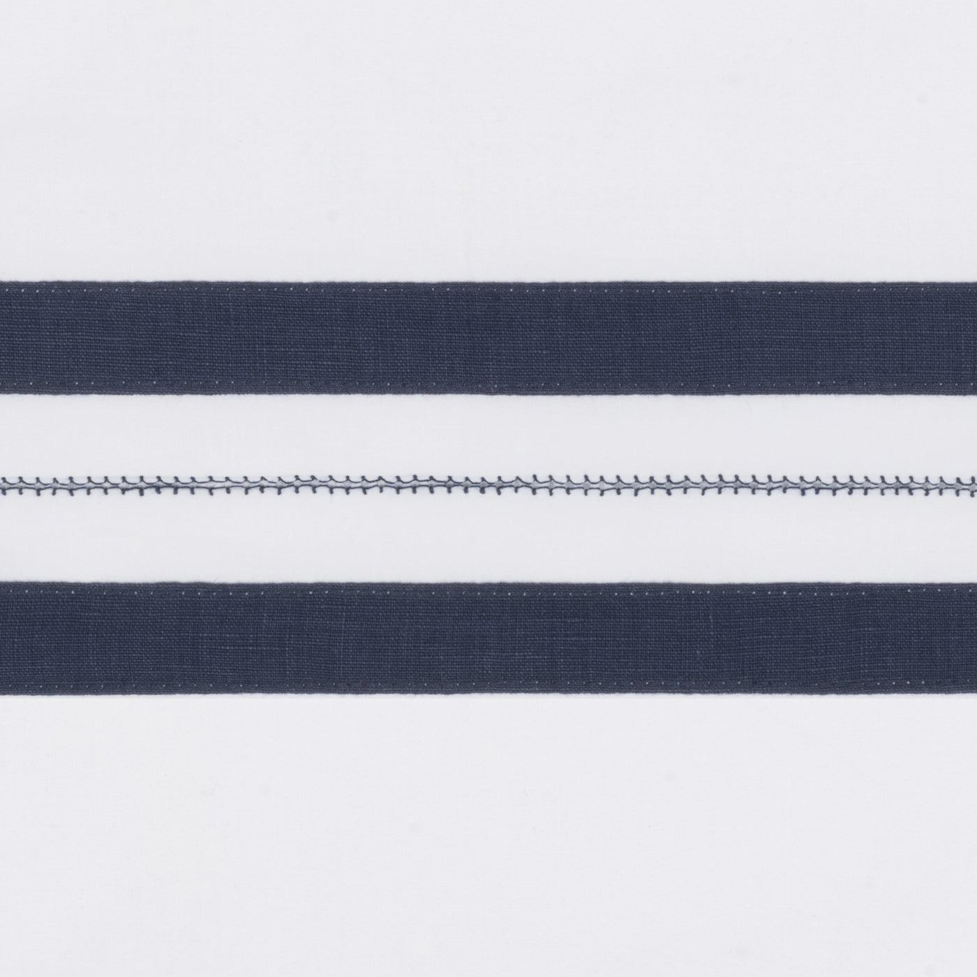 Close-up of navy stripes and hemstitch detail on white linen pillow sham.