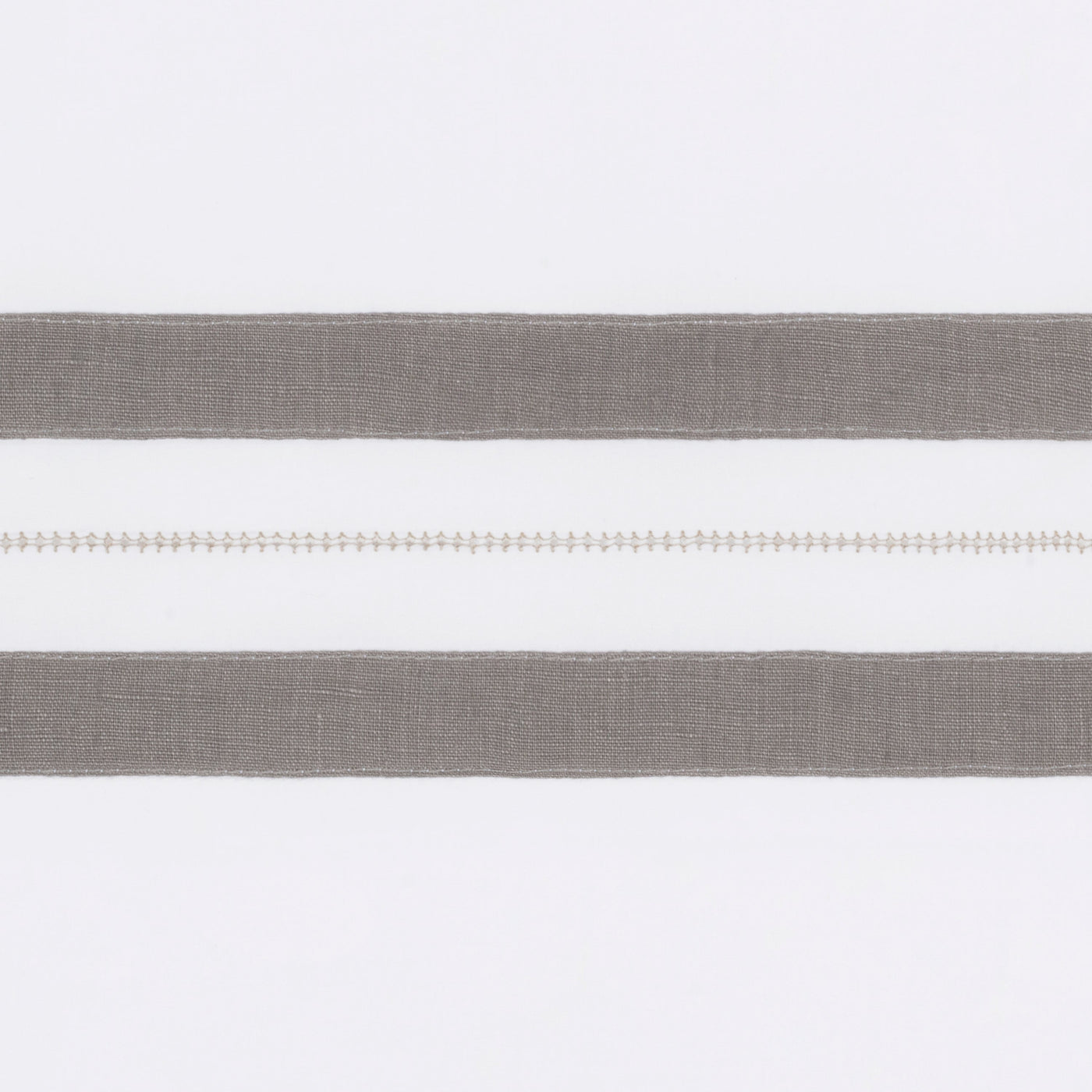 Close-up of dove grey linen bands with hemstitch detail on white ground.