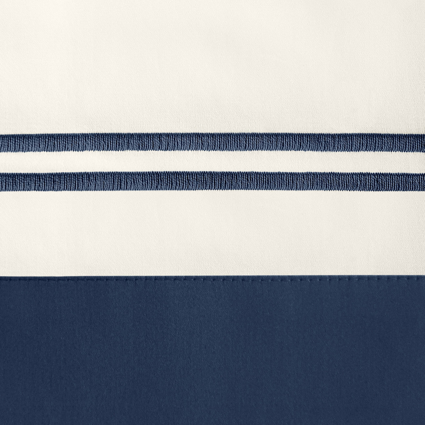 Close-up of navy embroidered double stripe detail on ivory and navy cotton duvet cover.