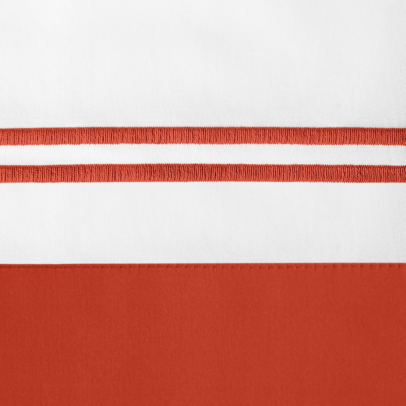 Close-up of white linen with terracotta embroidered double-stripe border detail.