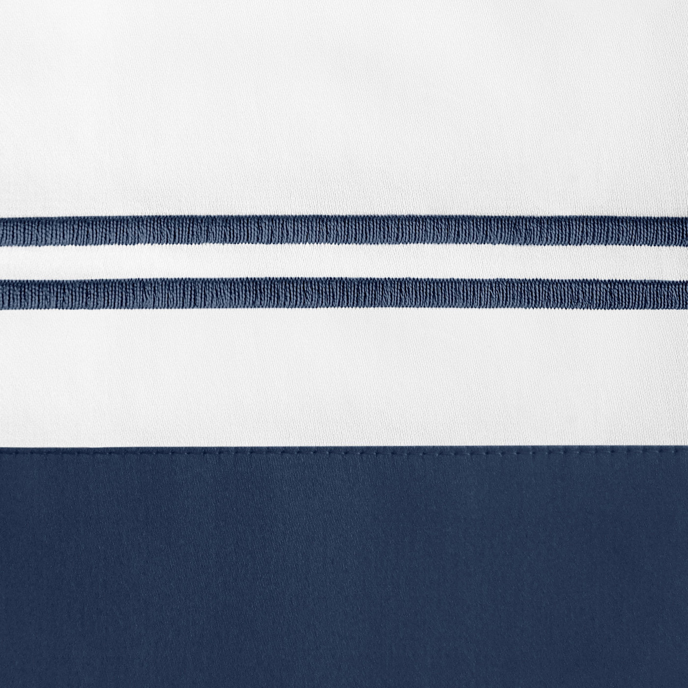 Close-up of navy border and embroidered double-stripe detail on white linen pillowcase.
