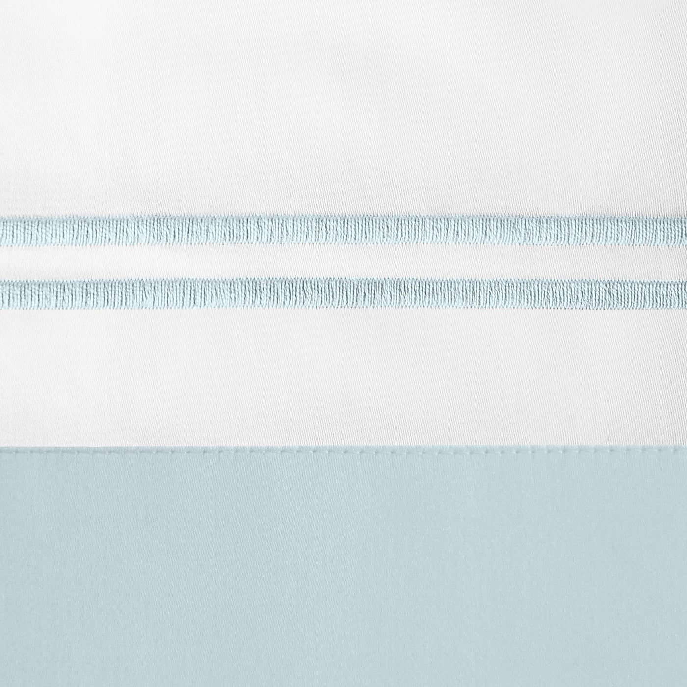 Close-up of white and sky blue cotton border with delicate fringe trim detail.