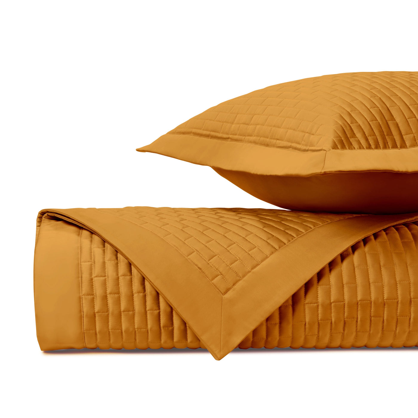 Saffron quilted weave texture close-up on folded coverlet and sham.