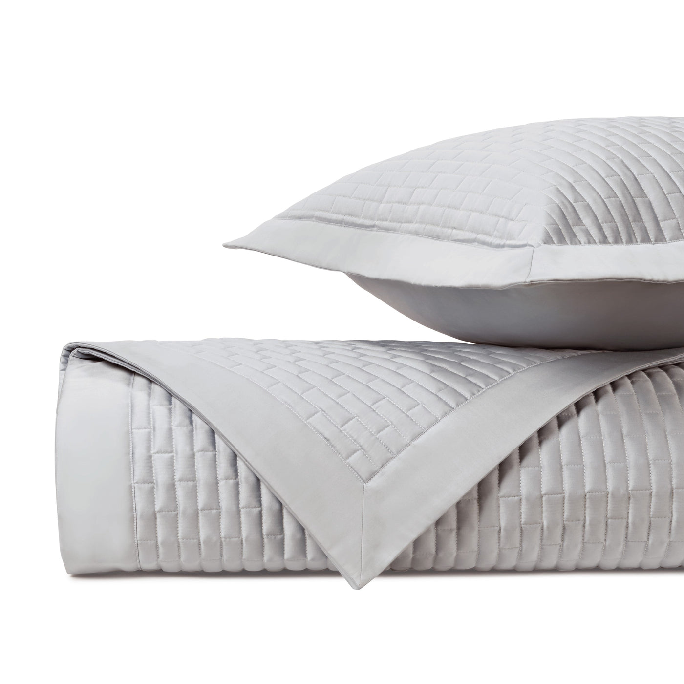 Close-up of silver quilted coverlet and sham showing basket-weave stitching pattern.
