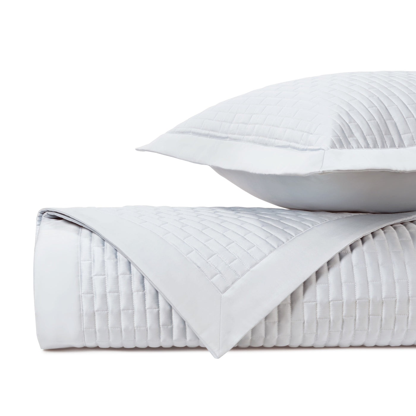 Close-up of Home Treasures Mason quilted white coverlet and sham, showing grid stitching detail.